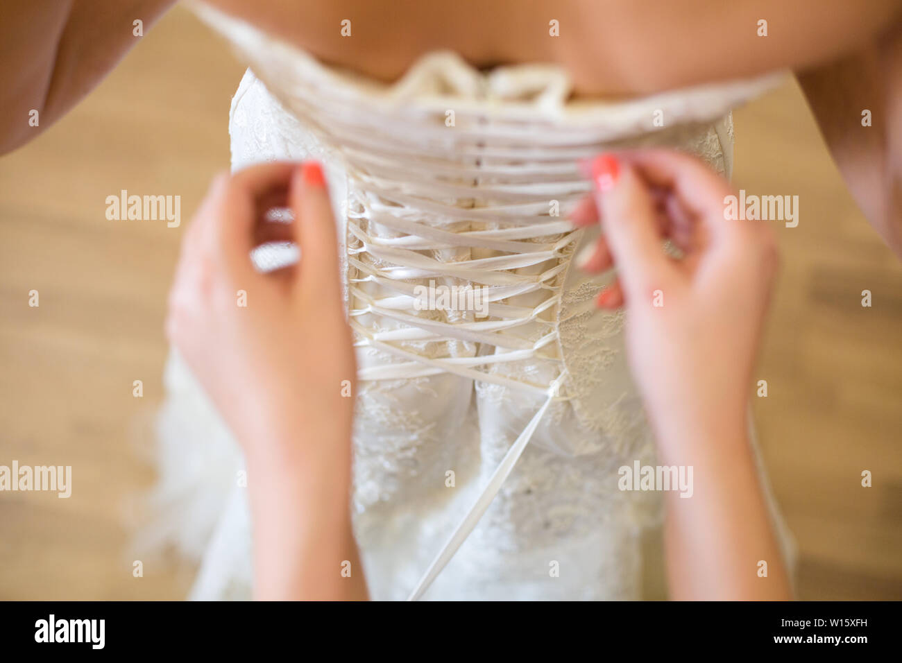 Bride from the back. Lacing the wedding dress Stock Photo - Alamy
