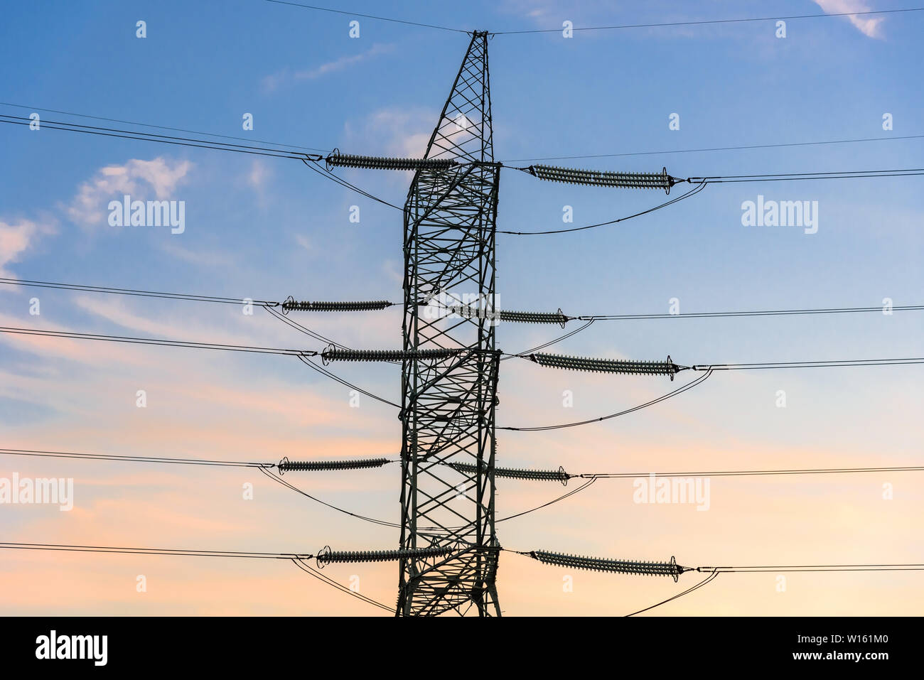 Closeup of electricity pylon and high voltage power lines at sunset ...