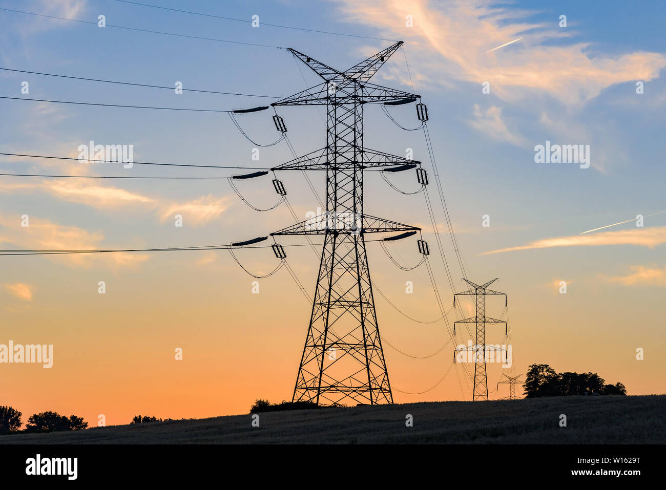 Electricity pylons and high voltage power lines at sunset Stock Photo ...