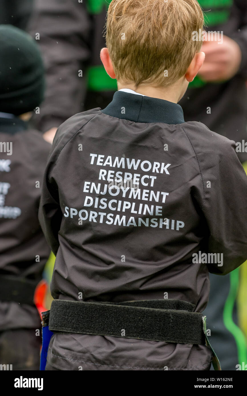 Young rugby player wearing a black jacket with the RFU rugby values of teamwork, respect, enjoyment, discipline and sportsmanship printed on the coat Stock Photo