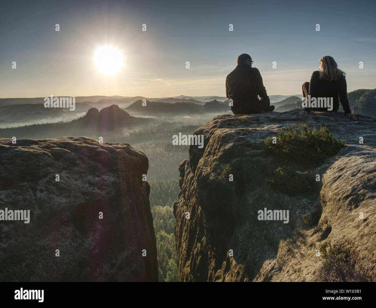 Silhouette woman and man shooting sunset on the top mountain. Relax ...