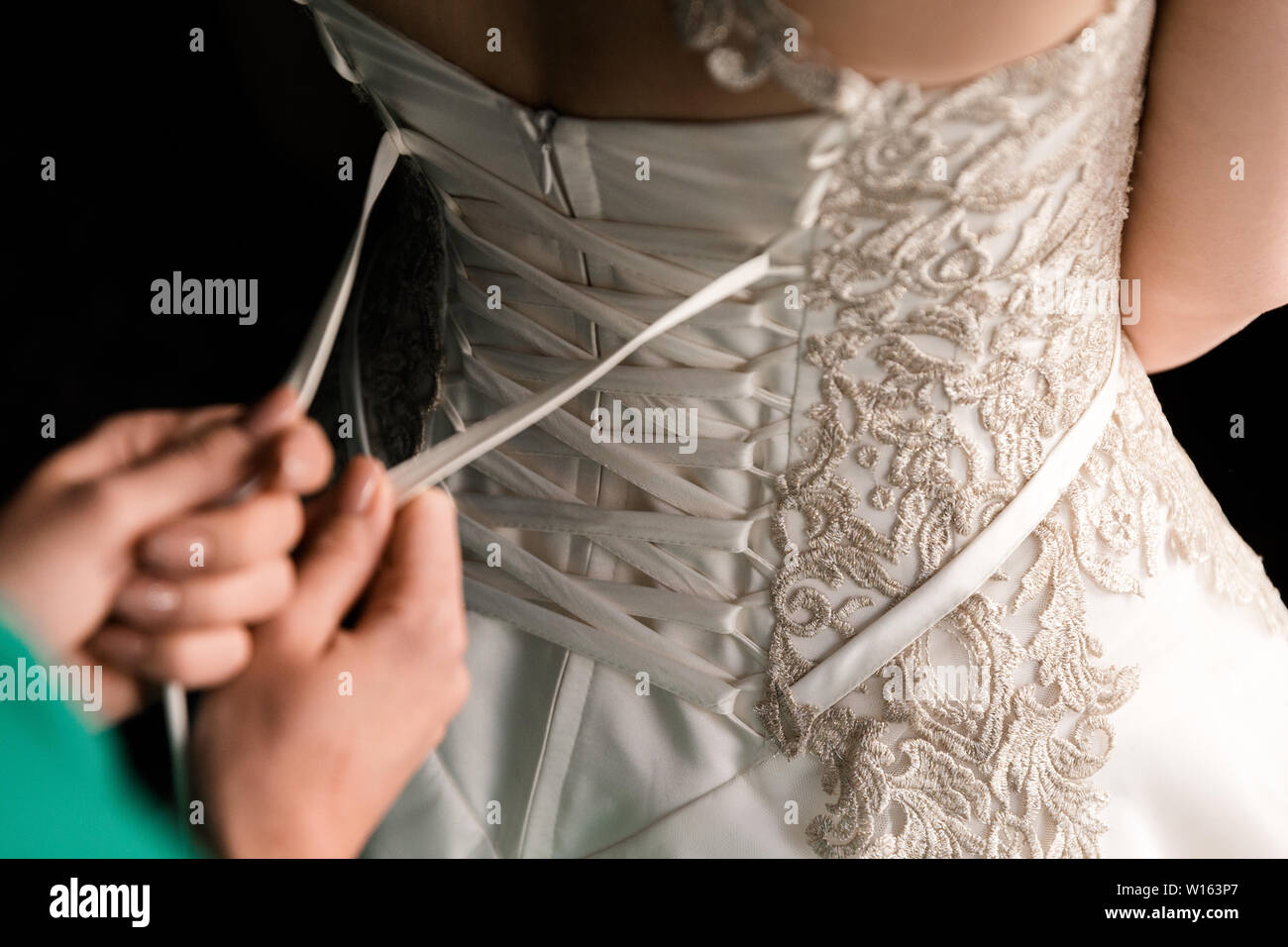 Bride from the back. Lacing the wedding dress Stock Photo - Alamy