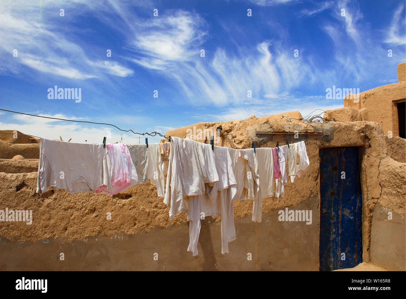 Clotheslines with white laundry on a brown loam house, under the blue sky of Marakech, Morocco. Stock Photo