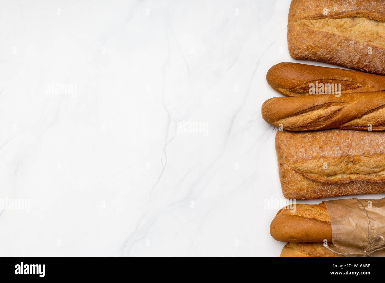 Different kind of breads on white marble background. Top view, horizontal right edge banner. Copy space for text Stock Photo