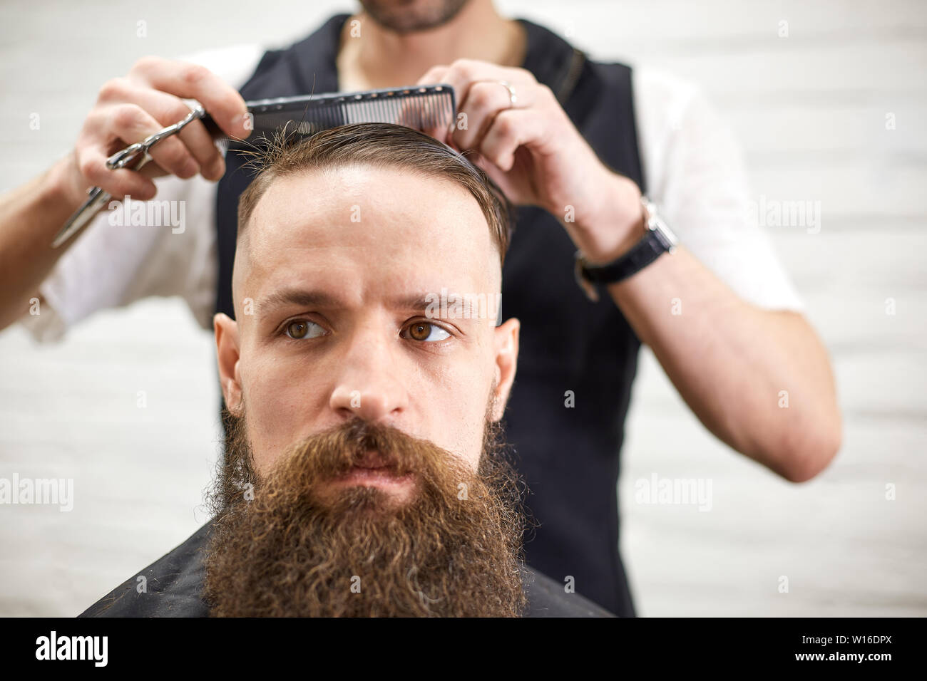 Brutal guy in modern Barber Shop. Hairdresser makes hairstyle a man