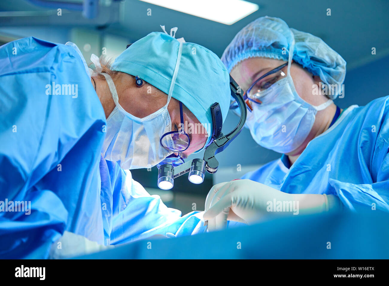 A surgeon's team in uniform performs an operation on a patient at a cardiac surgery clinic. Modern medicine, a professional team of surgeons, health. Stock Photo