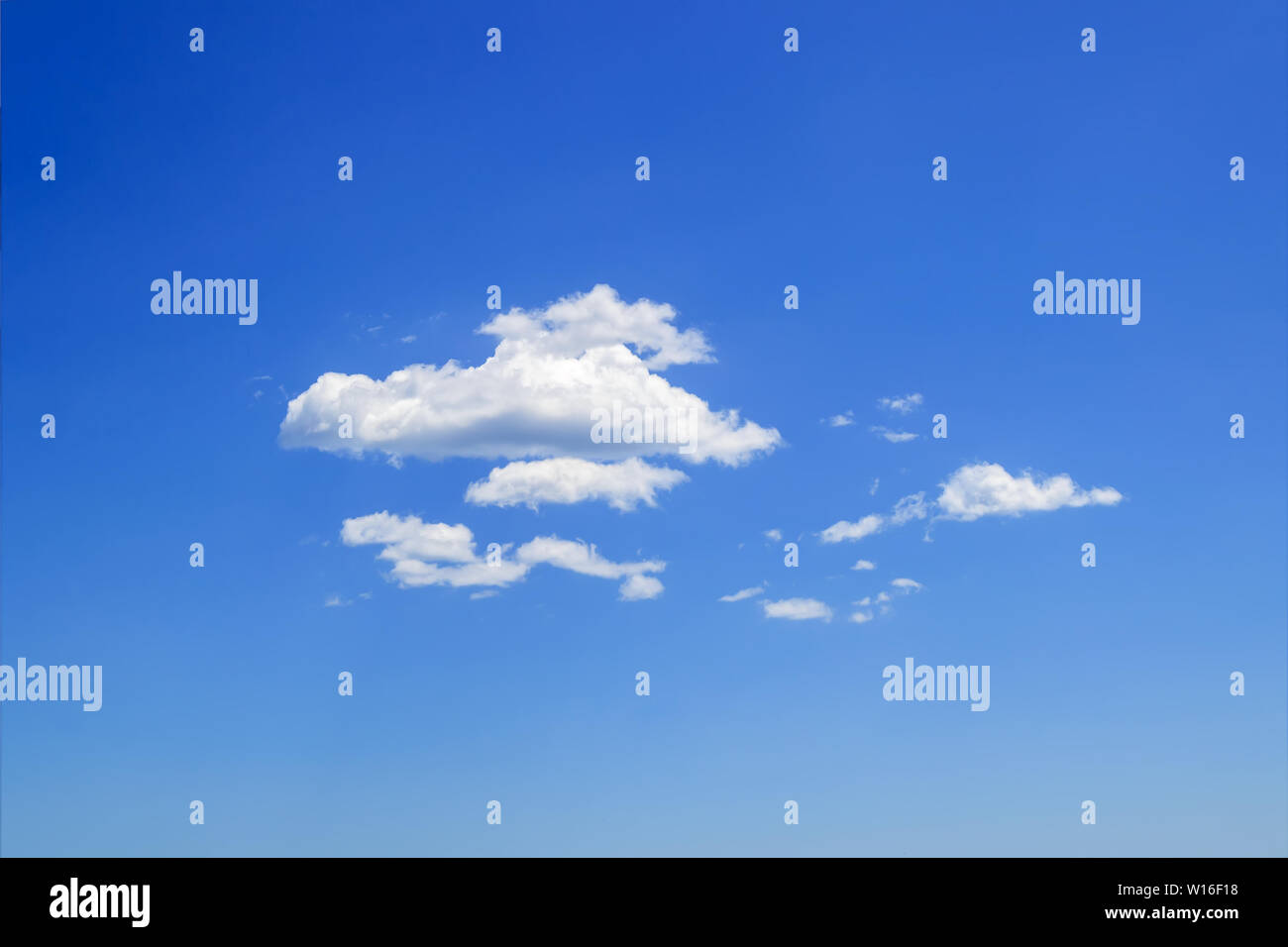 Scenic group of white fluffy cumulus clouds high in the blue summer sky ...