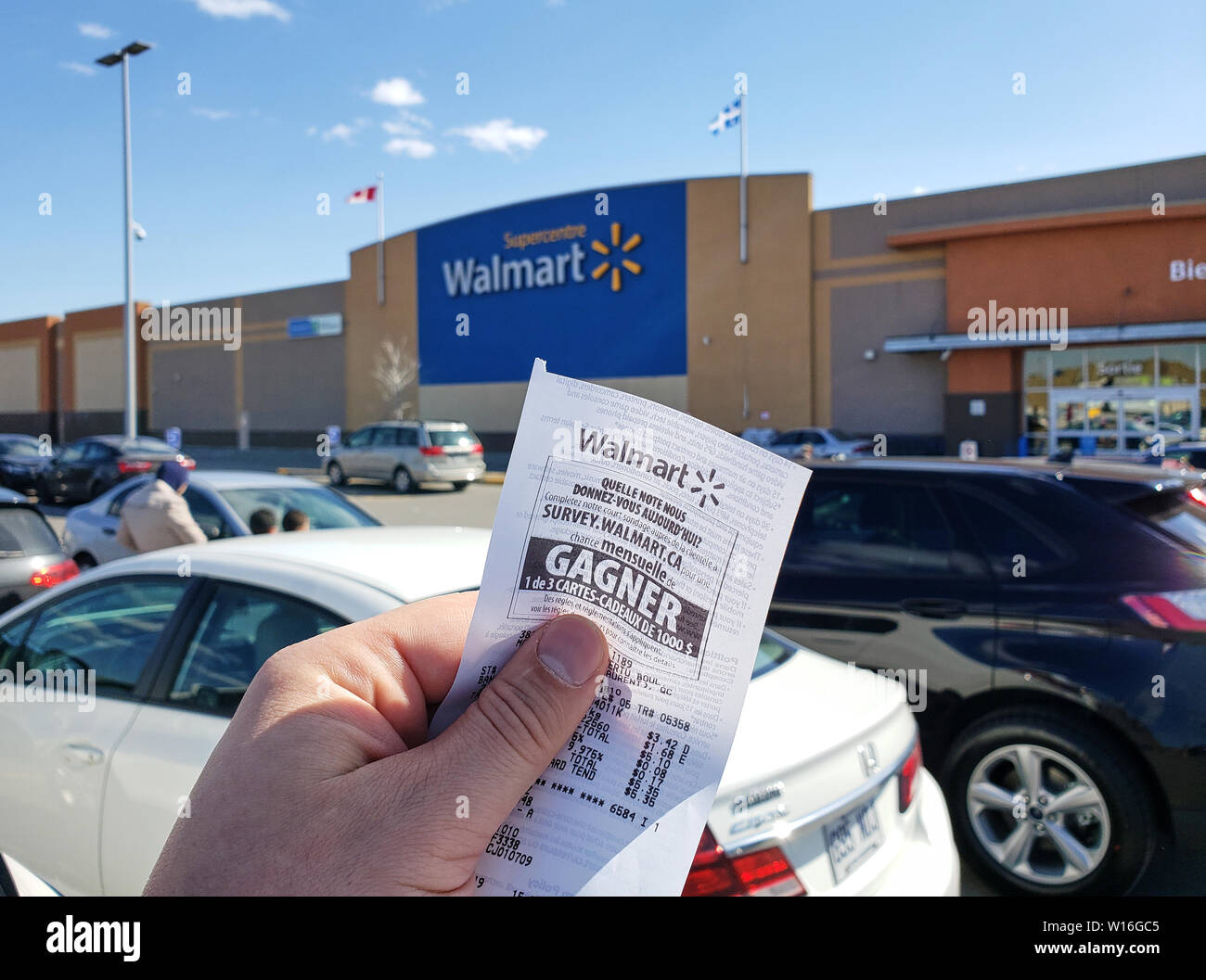 MONTREAL, CANADA APRIL 30, 2019 A hand holding a Walmart receipt in front of Walmart store