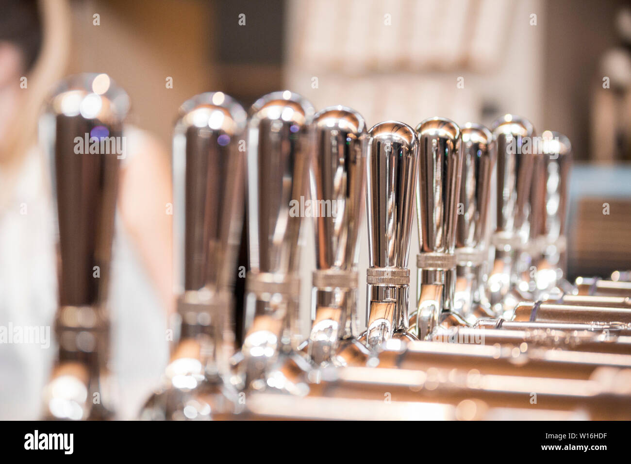 Row of silver beer taps in Vancouver brewery tasting room, with shallow depth of field. Stock Photo