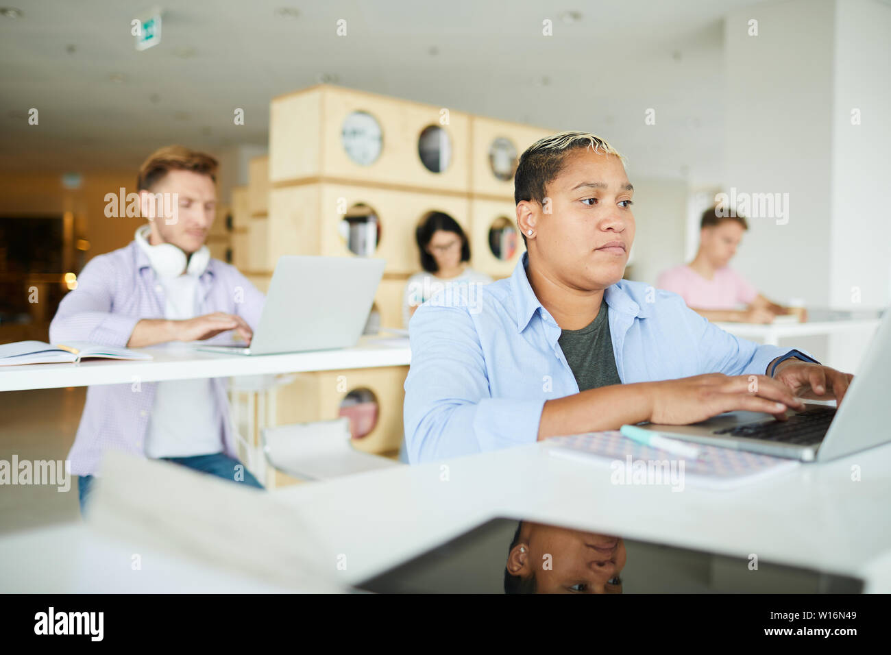 Serious busy young interracial entrepreneurs sitting in co-working space and using modern laptops while working with data Stock Photo