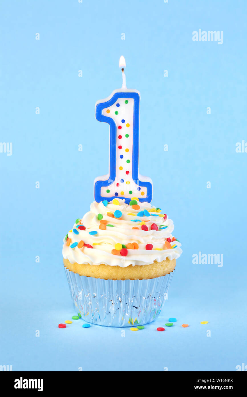 Iced birthday cupcake with with lit number 1 candle and sprinkles Stock Photo