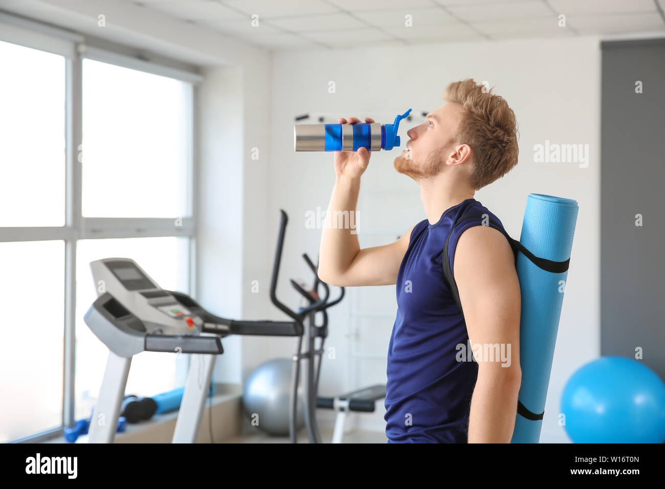 Sporty young man drinking water in gym Stock Photo - Alamy