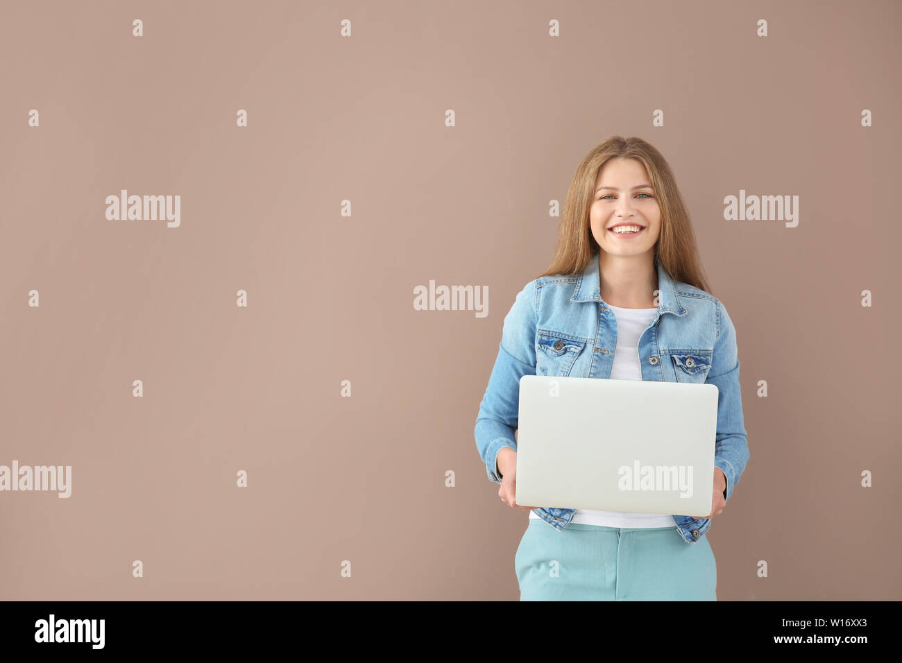 Beautiful young woman with laptop on color background Stock Photo - Alamy