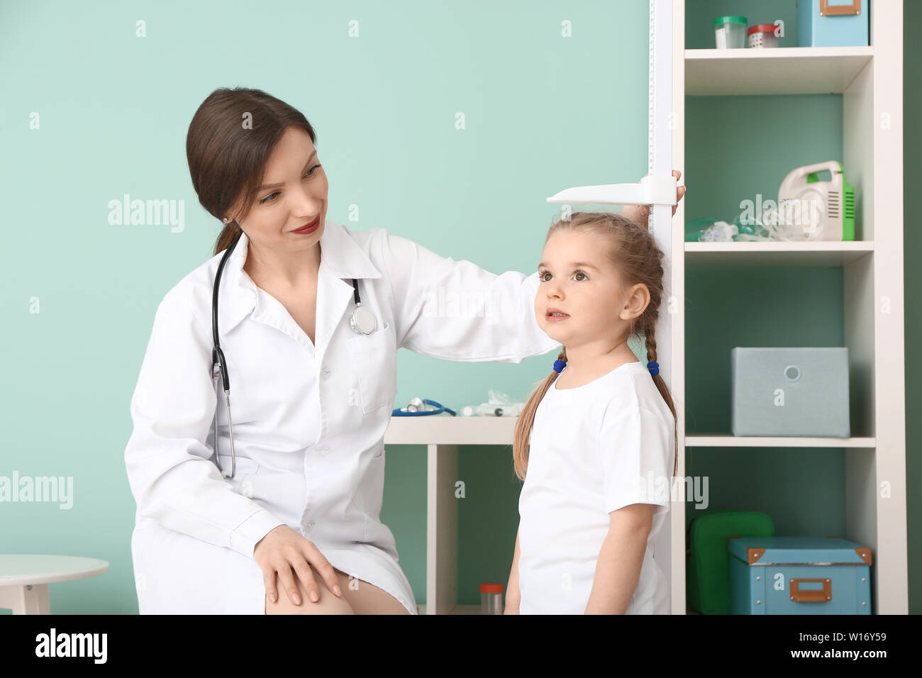 Female doctor measuring height of little girl in hospital Stock Photo