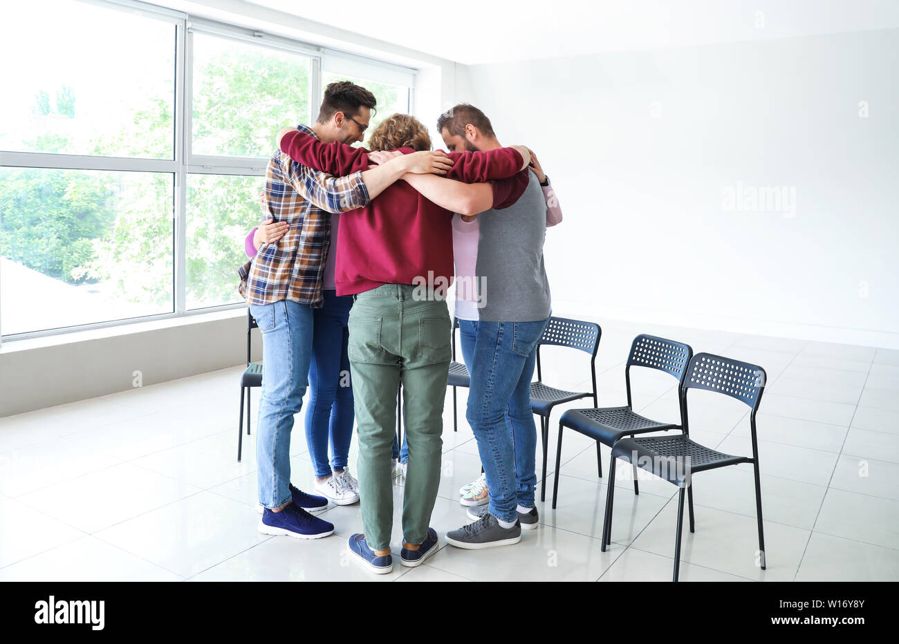 Young people hugging together at group therapy session Stock Photo