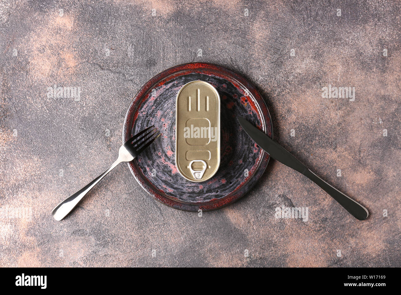 Tin can with plate and cutlery on grey background Stock Photo