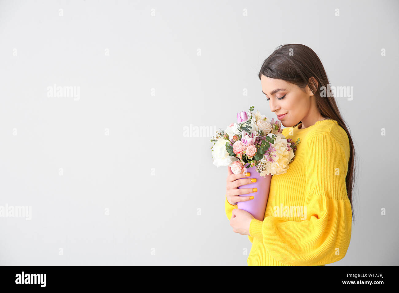 Beautiful young woman with bouquet of flowers on light background Stock ...
