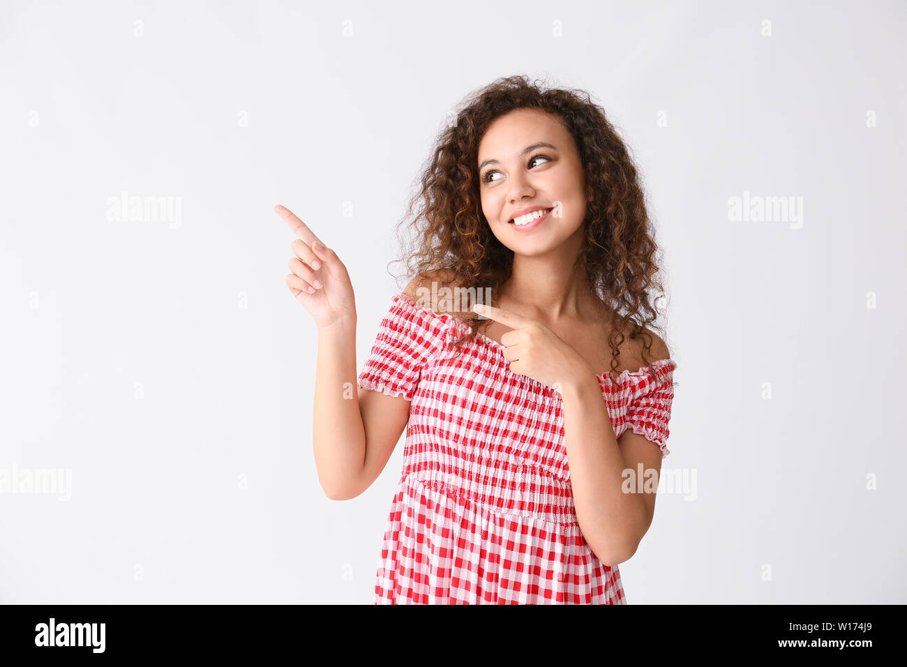 Beautiful African-American woman pointing at something on white ...