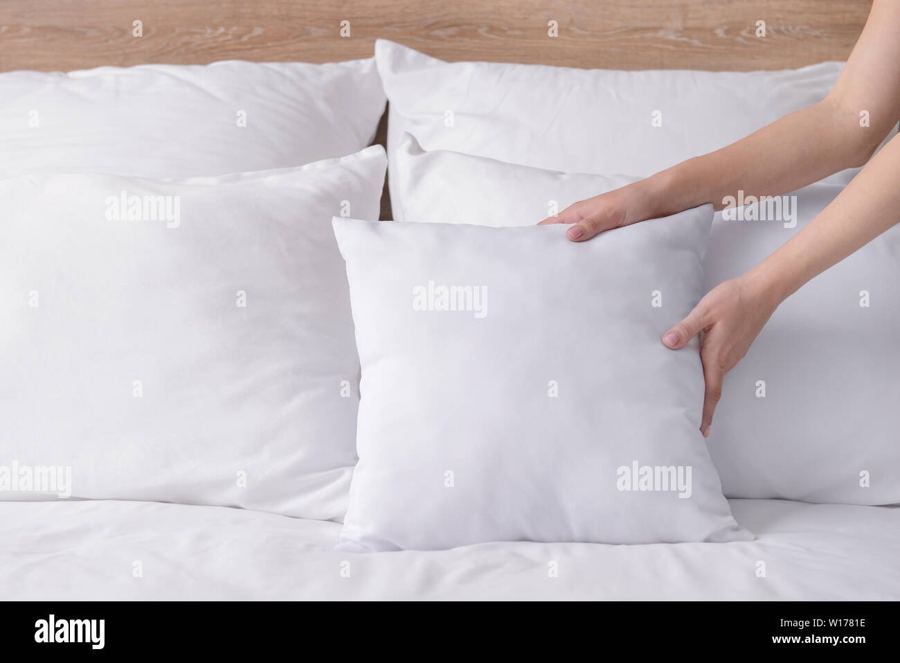 Woman fluffing soft pillows on bed Stock Photo Alamy