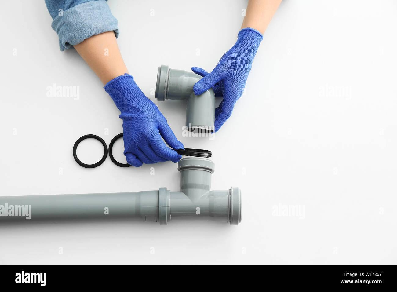 Plumber working with drain pipe on white background Stock Photo