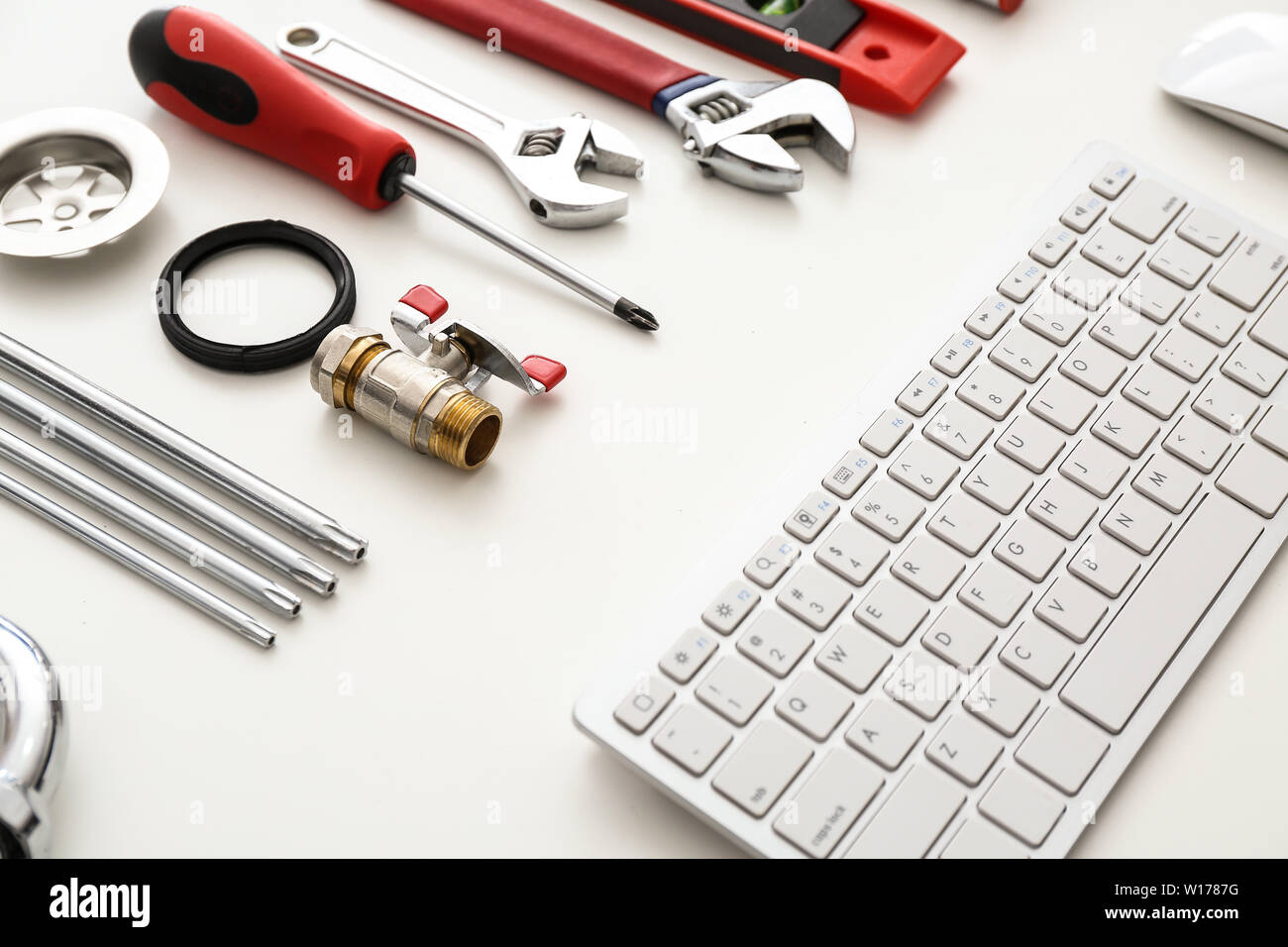 Computer keyboard and plumbing items on white background Stock Photo