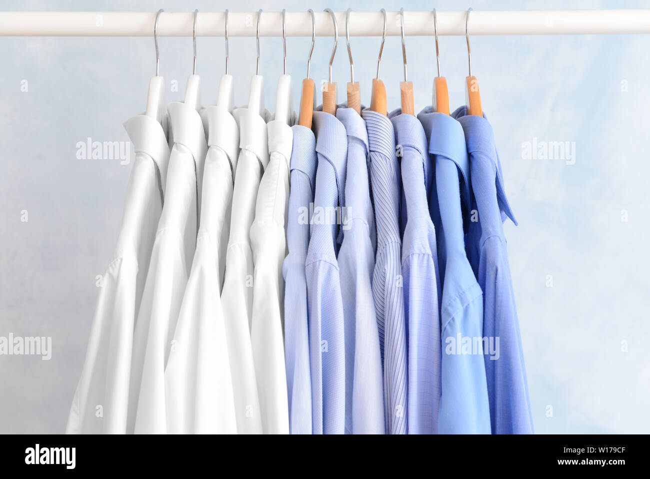 Rack with clothes after dry-cleaning on light background Stock Photo