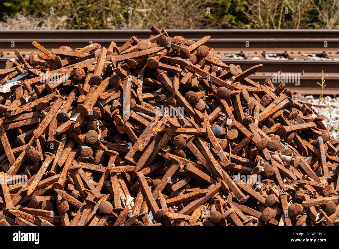 A pile of rusted scrap railroad spikes and fasteners awaiting recycling