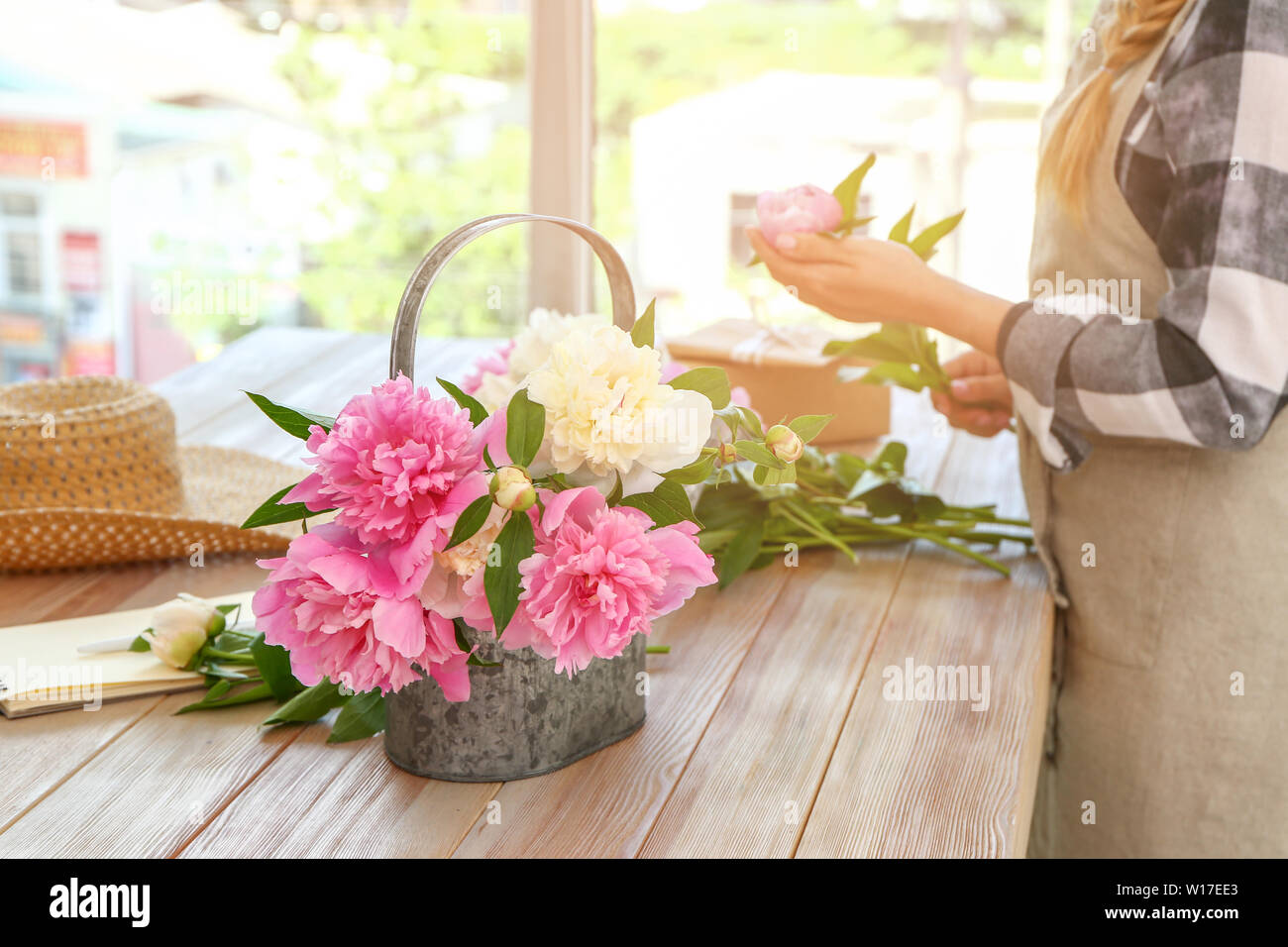 Watering can with beautiful peonies on table of florist Stock