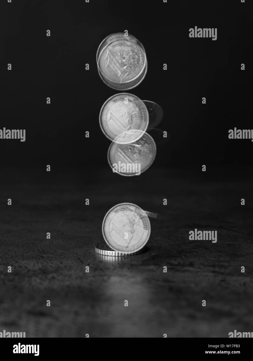 Stroboscopic photo of falling coin on dark background Stock Photo