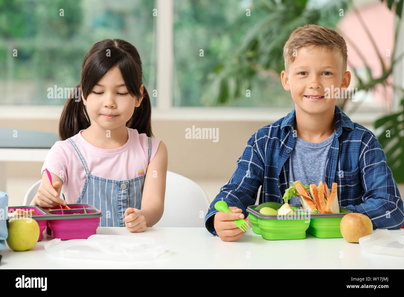 Schoolchildren having lunch in classroom Stock Photo - Alamy