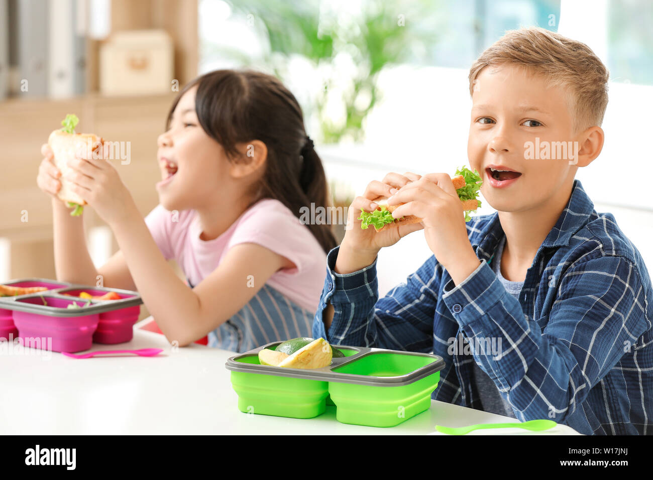 Schoolchildren having lunch in classroom Stock Photo Alamy