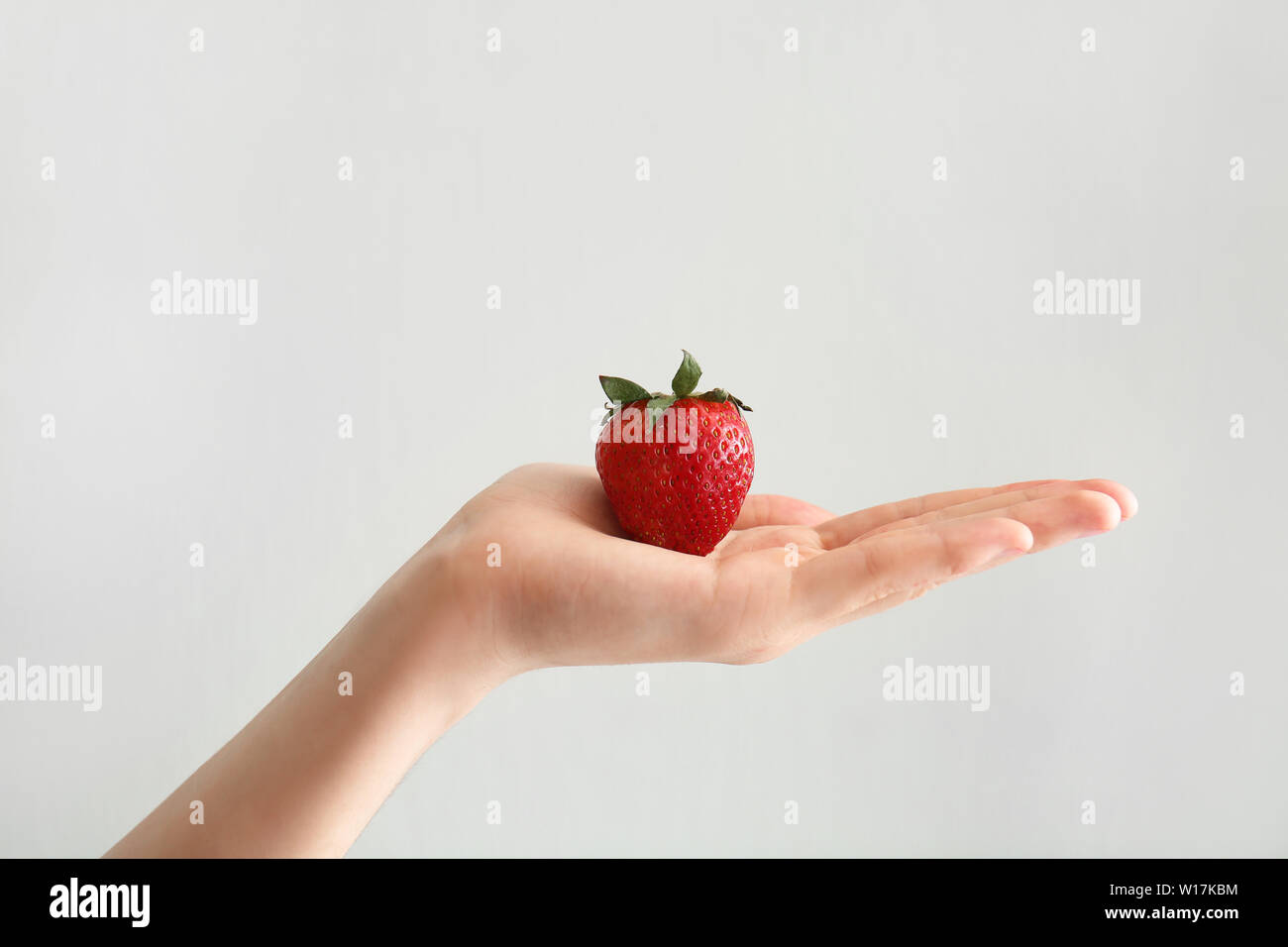 Female hand with ripe strawberry on white background Stock Photo - Alamy