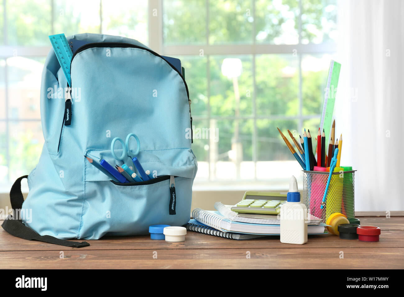 School backpack with stationery on table in room Stock Photo