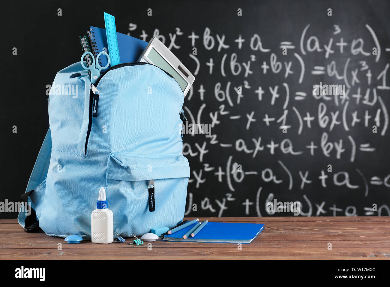 School backpack with stationery on table in classroom Stock Photo