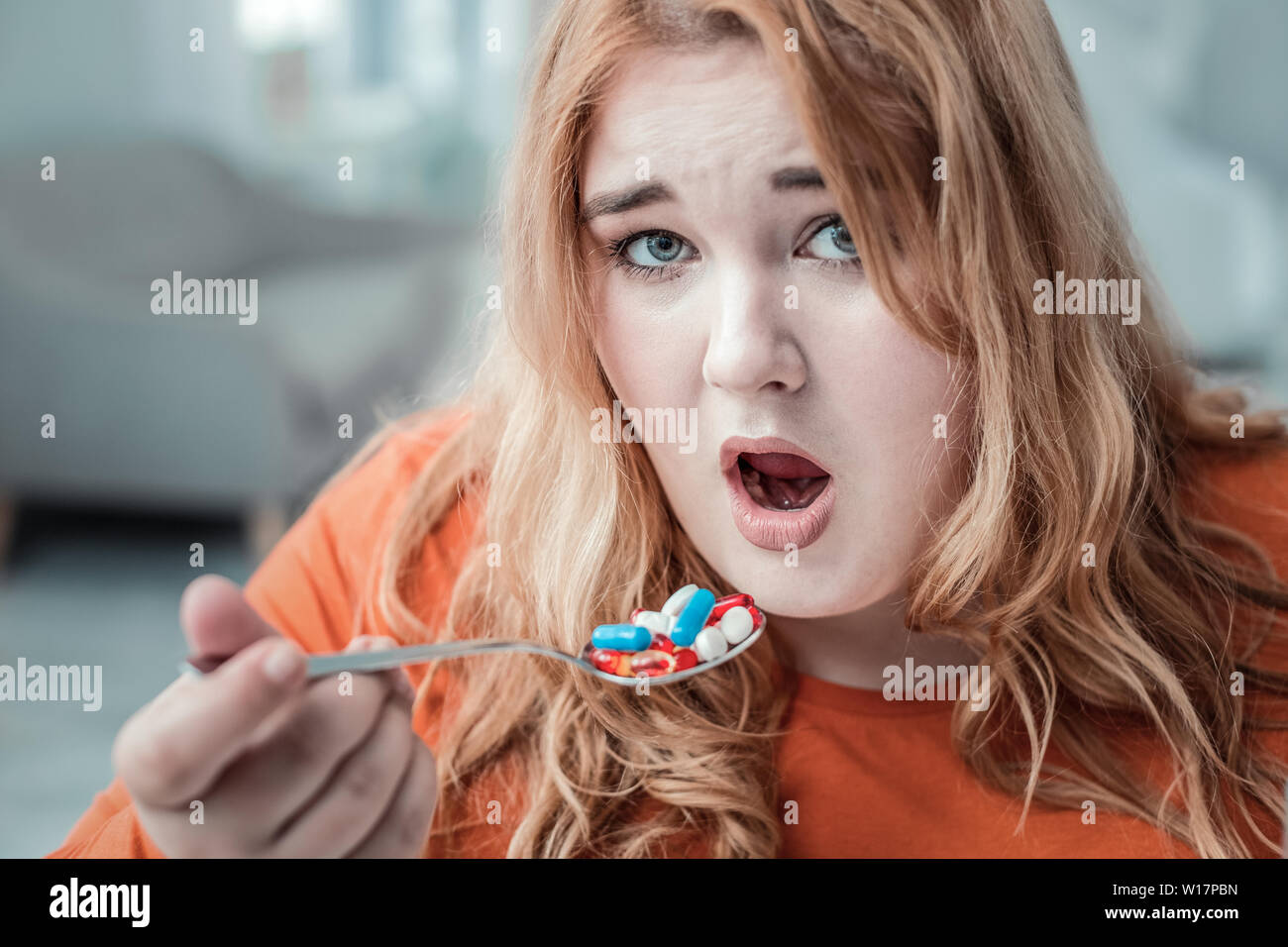 Emotional plump woman taking vitamins before dinner Stock Photo Alamy