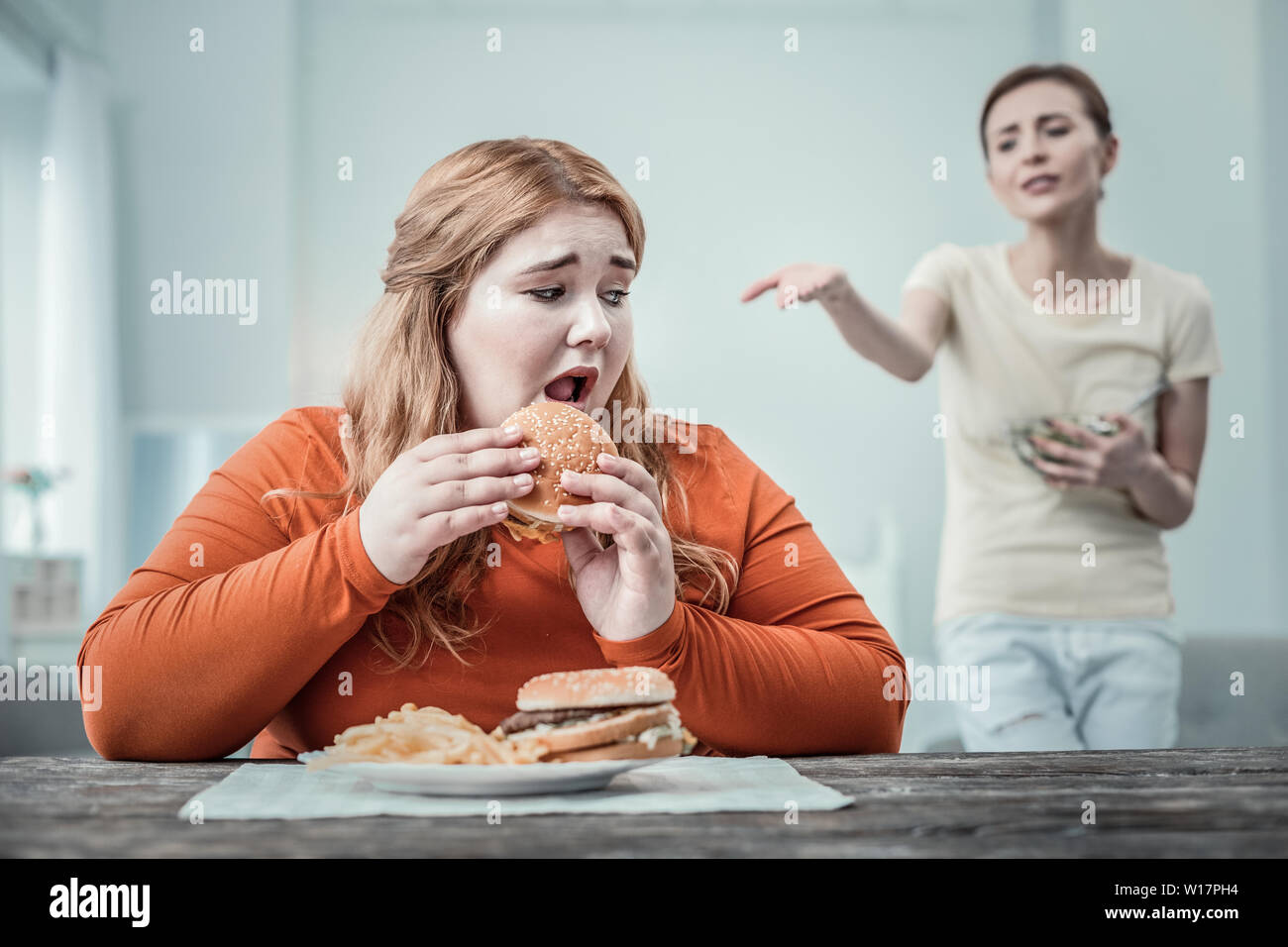 Emotional girl being afraid to eat fast food Stock Photo Alamy