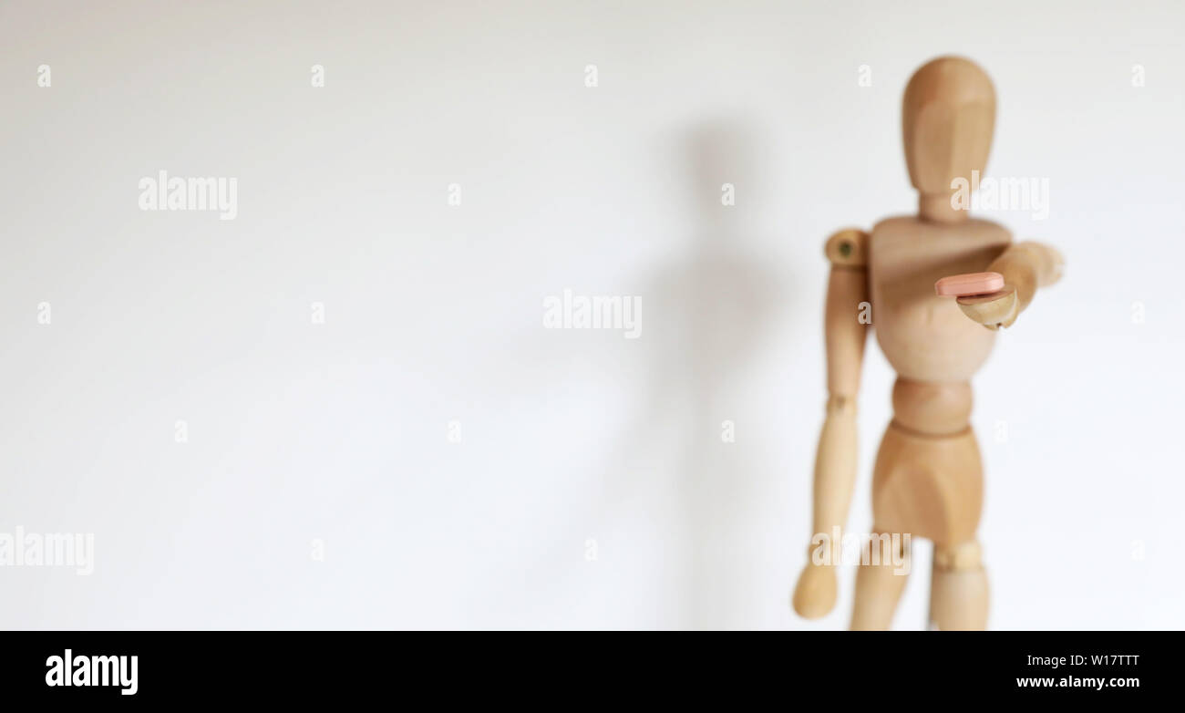 Single solo individual wooden mannequin figure offering dealing a pill drug to the viewer. Personal choice decision. Self harm damage and consequence Stock Photo