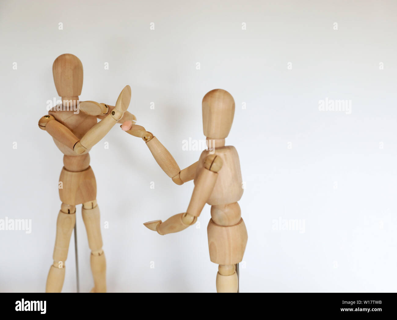 two wooden mannequin figures dealing and saying no to party drugs pills. Pill testing at music festival concept. Making healthy personal life choices Stock Photo
