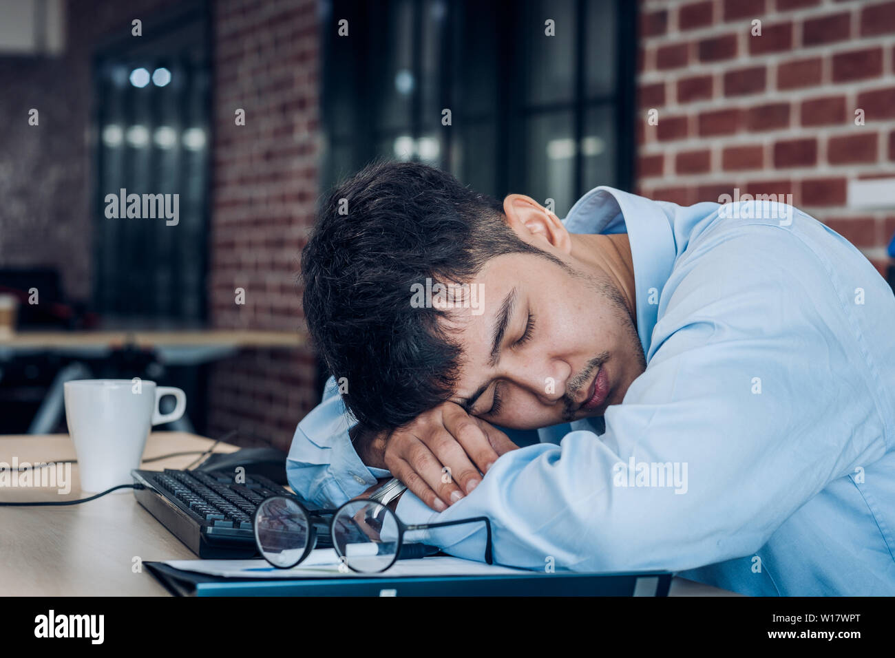 Tired asian businessman sleep on working desk table in office.working