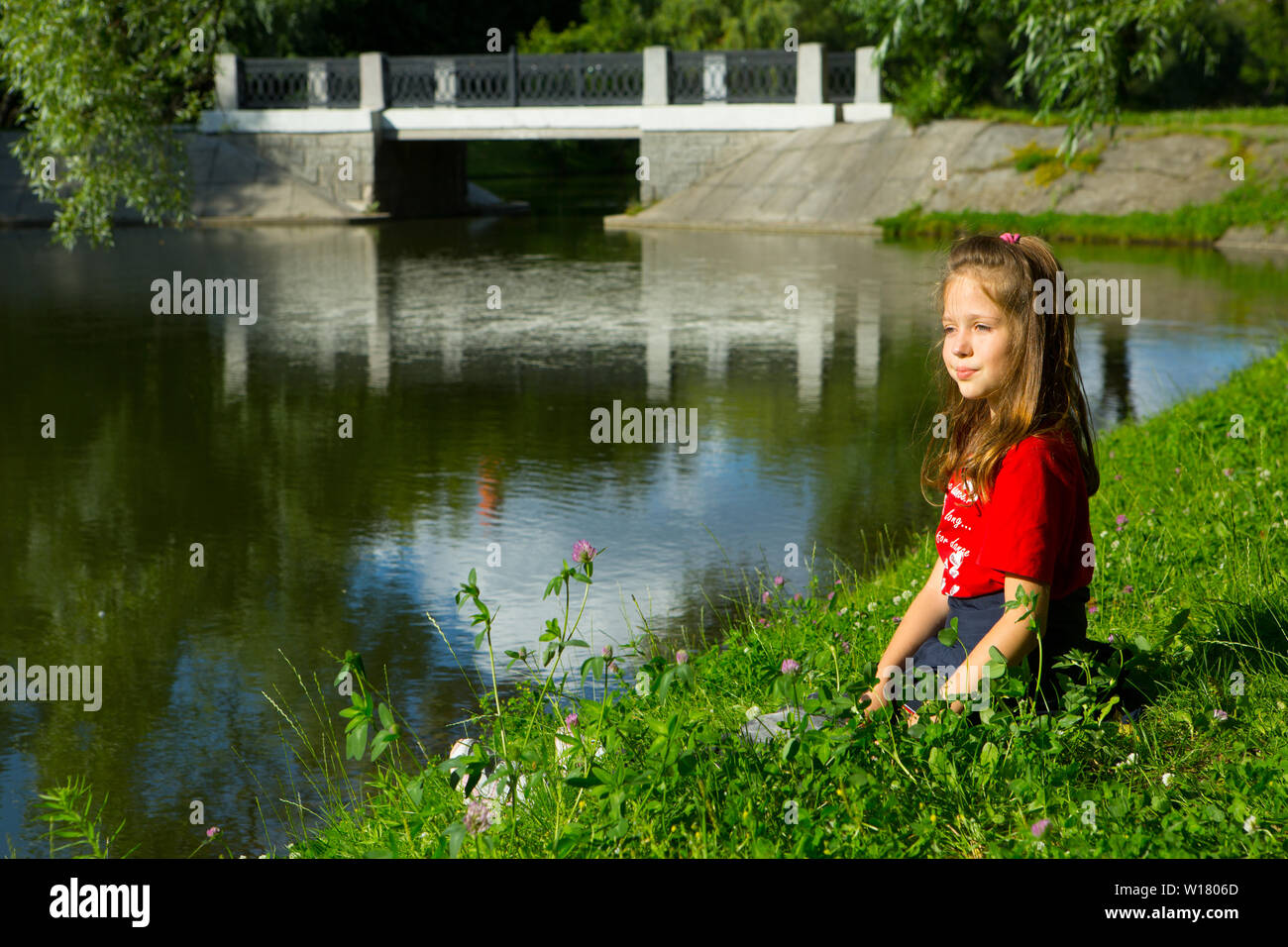 Girl sitting on the river bank Stock Photo - Alamy