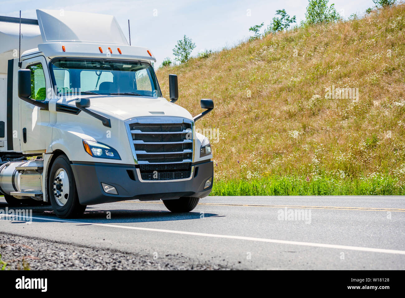 Big rig white day cab semi truck with roof spoiler and chrome grille