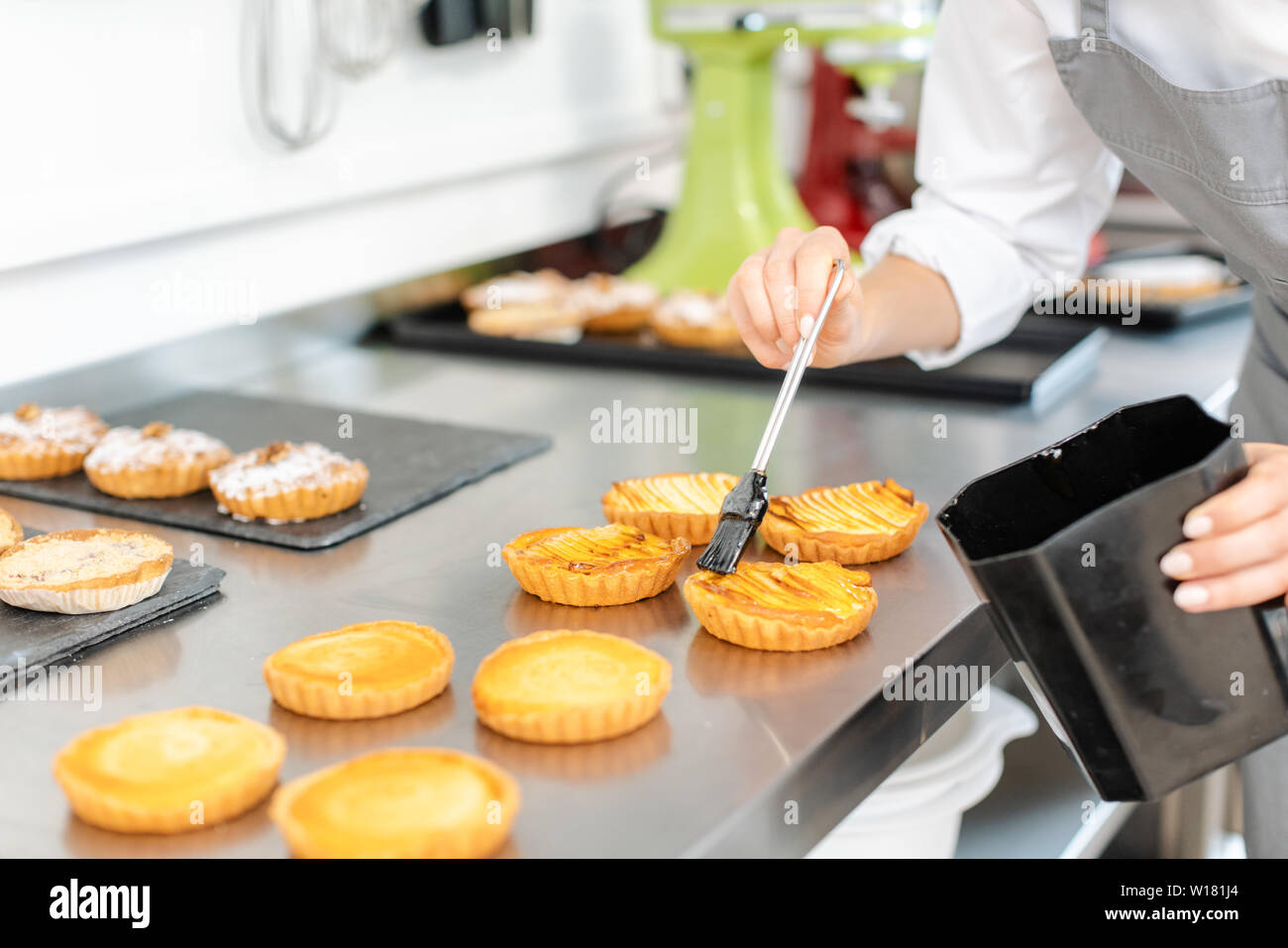 Pastry chef woman glazing little cakes Stock Photo