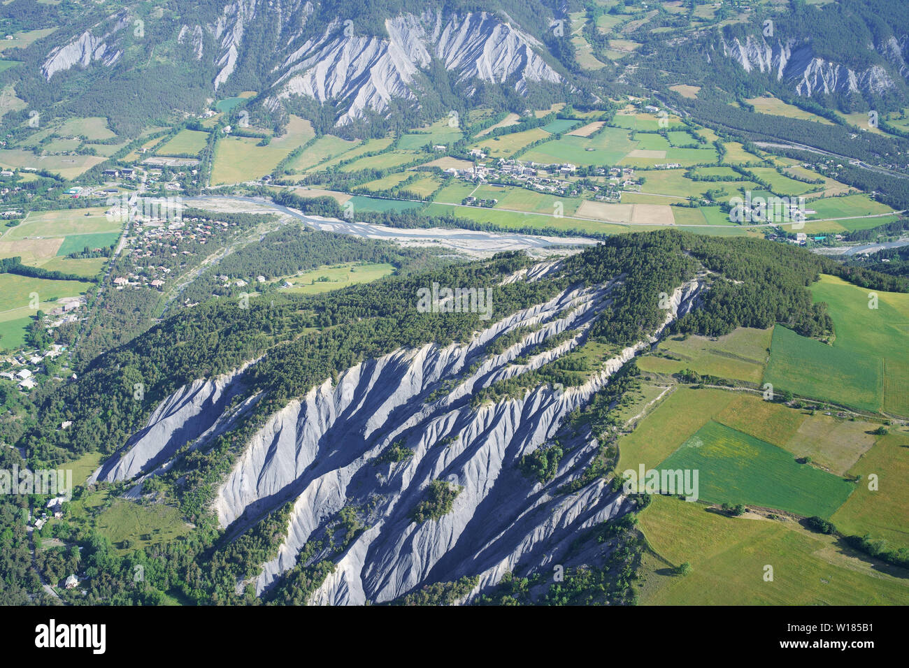 AERIAL VIEW. Landscape of ravines and farmlands of the Ubaye Valley. Barcelonnette, Alpes-de-Haute-Provence, France. Stock Photo
