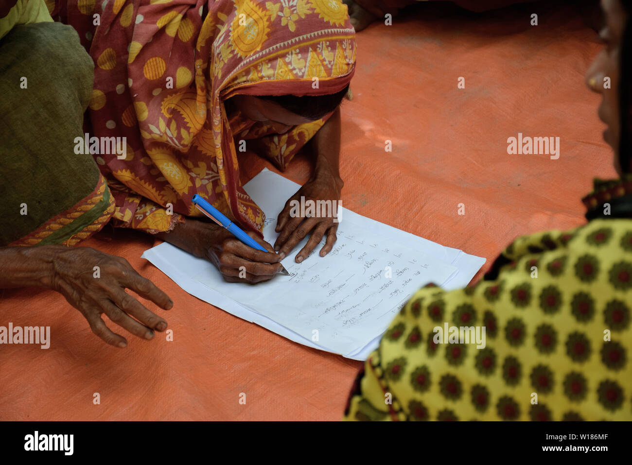 poor village woman writes her name in Bangladesh as a part of woman literacy campaign Stock Photo