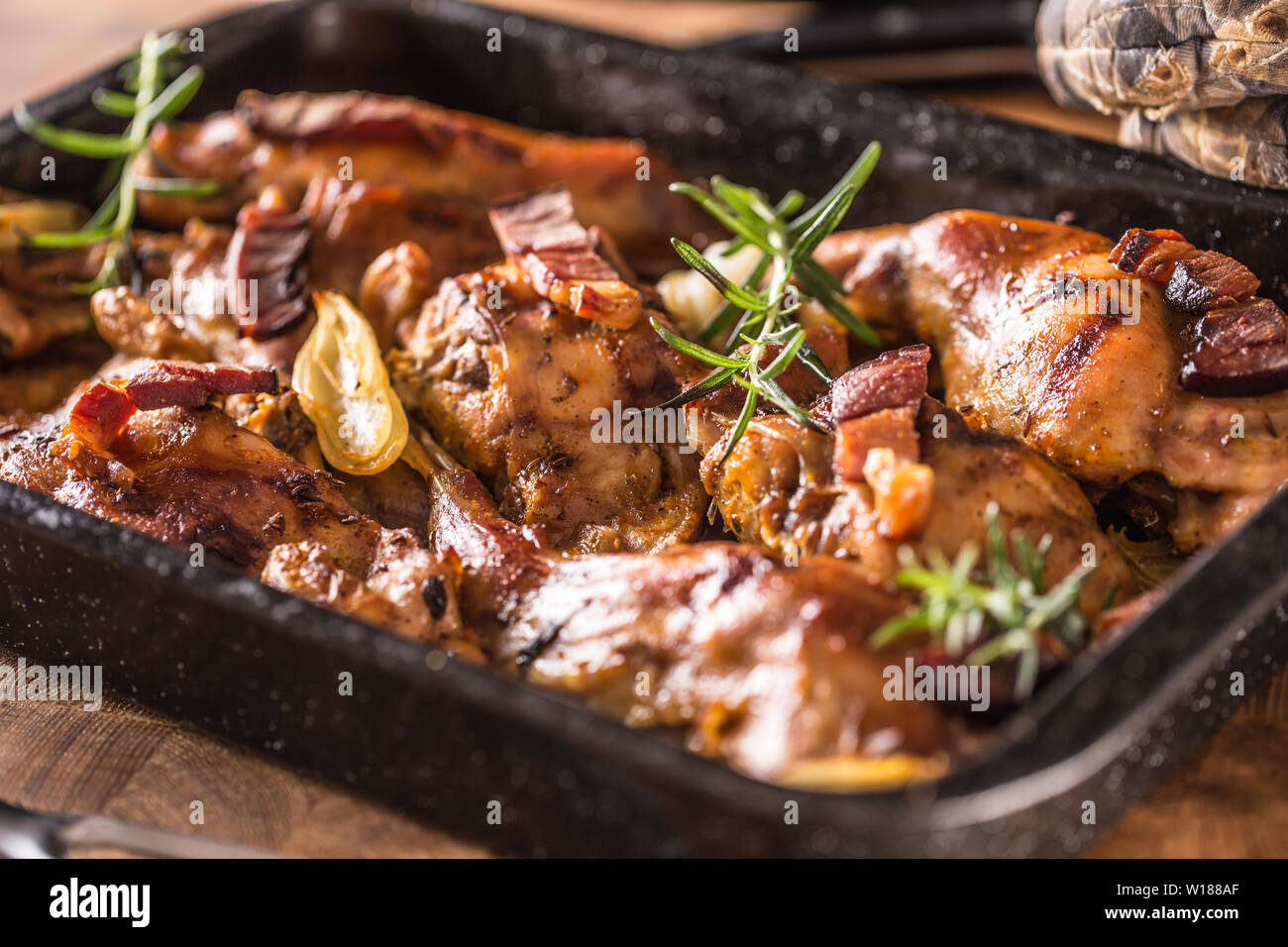 Portioned baked rabbit in a pan with onion rosemary and sauce Stock ...