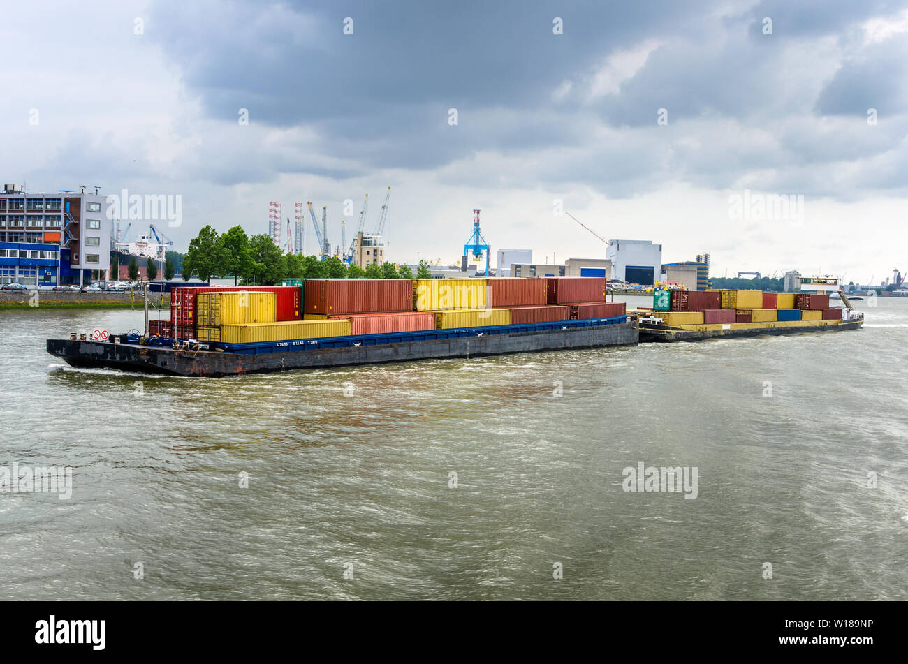 Barge Loaded with Colourful Container in the Port of Rotterdam on a Spring Cloudy Day Stock Photo