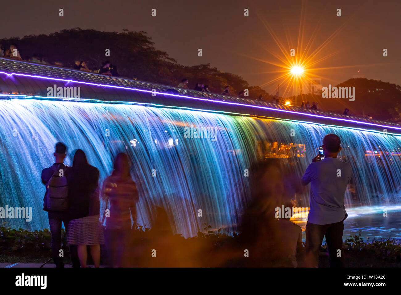 People enjoying the Starlight Bridge or anh sao bridge in phu my hung district of Ho Chi Minh City Vietnam. It is a solarpowered illuminated waterfall Stock Photo