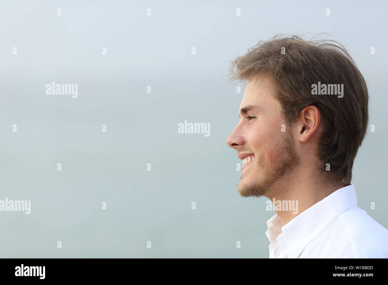 Side view portrait of a happy man looking away on the beach Stock Photo