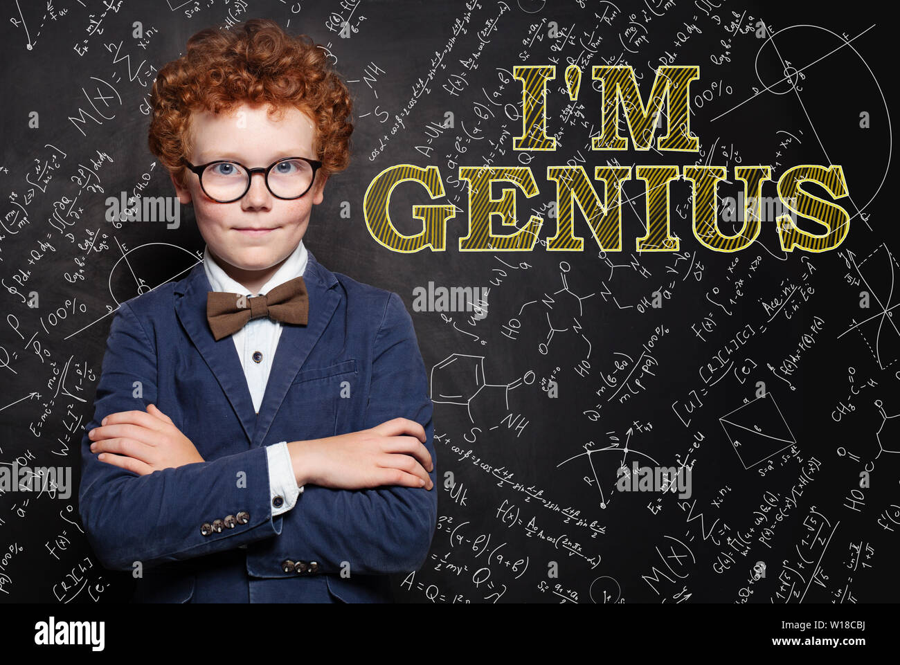 Smart kid genius on chalkboard background with science and maths formula Stock Photo