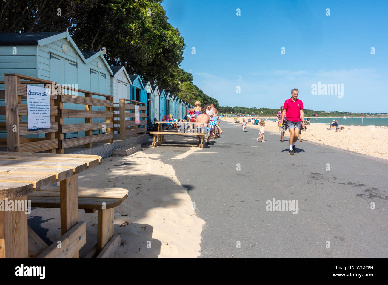 Row of beach huts in different pastel blue shades run along the top of Avon Beach at Mudeford, Christchurch in Dorset, UK. A sandy beach with pebbles. Stock Photo